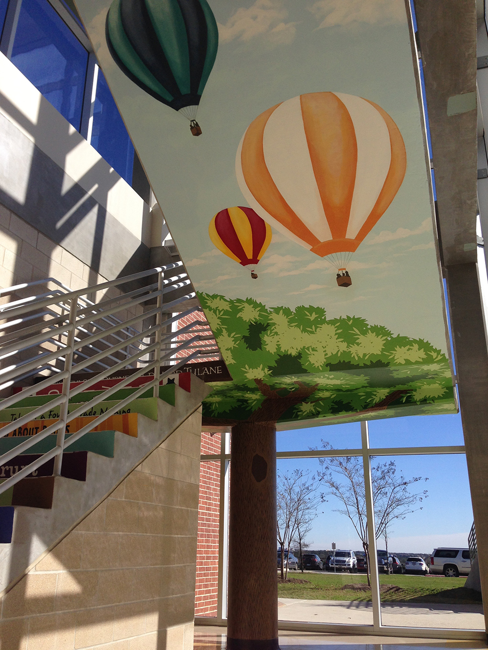 Painted hot air balloons and tree canopy above the stairwell.