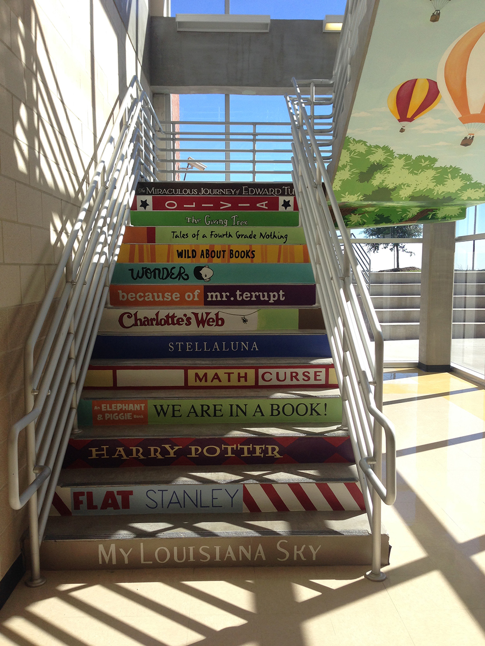 Stair risers painted as a stack of children's book spines.